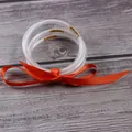 Detailed shot of clear glitter jelly bangles with orange ribbon on grey wood background. - 5 Piece Set / Orange