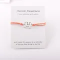 Autism Awareness verzilverde puzzelarmband op displaykaart met een oranje waskoord - Oranje