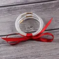 Detail of clear glitter jelly bangles with a red ribbon on wooden background - 5 Piece Set / Red
