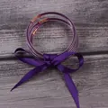 Vue rapprochée de trois joncs à paillettes violettes avec un nœud en ruban de soie - Ensemble à 3 couches / Violet