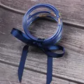Close-up of 7-layer blue glitter silicone bangles tied with a satin ribbon. - Blue