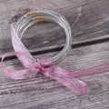 Detail van zilveren glitter jelly armbanden set vastgeknoopt met een decoratief roze lintje. - 5 Stuks / Zilver (JB604)