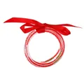 Primer plano de pulseras de gelatina rojas con purpurina y un lazo decorativo de cinta - Julio