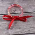 Primer plano de pulseras de silicona con purpurina roja y un lazo de cinta de seda. - Julio Rojo