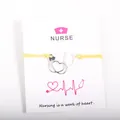 Yellow wax rope bracelet with silver stethoscope pendant on a white nurse themed gift card. - Yellow