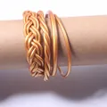 Detailed close-up view of a four-piece set of golden braided jelly bangles on a brown tube - Set of 4 / Antique Gold