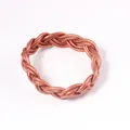 Détail en gros plan d'un bracelet jonc tressé en silicone cuivré - Or rose