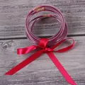 7-piece set of purple glitter silicone jelly bangles with a red satin bow - Fuschia