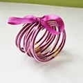 Close-up detail of a stack of purple glitter jelly bangles tied with a purple silk ribbon bow - 9 Pieces Set / Magenta