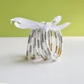 Close-up of nine jelly bangles with black patterns and gold accents tied in white ribbon - 9 Pieces Set / Classic Leather Pattern