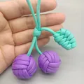 Détail macro d'un porte-clés cerise tissé à la main avec cordon violet et bleu sarcelle - Violet