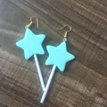 Detailweergave van schattige cyaan ster lolly oorbellen met witte stokjes op houten vla - Blauw