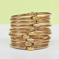 Vista dettagliata di dieci braccialetti jelly con glitter dorati e ciondoli a forma di loto - Confezione da 10 / Oro champagne