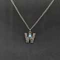 Macro view of a vintage silver necklace with a W-shaped pendant and turquoise stone. - Letter W