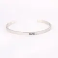 Detailed close-up view of a silver stainless steel cuff bracelet with DAD engraving - DAD