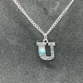 Close-up of vintage silver 'U' initial pendant with turquoise and stamped patterns. - Letter U