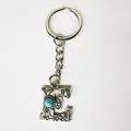 Detail shot of a retro silver stainless steel letter E keychain featuring a turquoise stone - Letter E