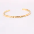 Macro detail of 'LOVE INSPIRE TEACH' engraving on minimalist gold stainless bracelet - LOVE INSPIRE TEACH Engraved Style / Gold