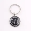Close-up of a circular Viking keychain with Norse runes and symbols on a black base. - Black/White Rune / Silver