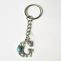 Macro detail view showing the engraved patterns of a vintage silver letter G keychain. - Letter G
