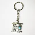 Close-up of retro silver initial H keychain with turquoise and western engravings - Letter H