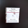 Close-up of red string bracelet with apple charm on teacher appreciation wish card - Red