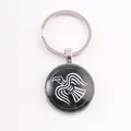 Macro detail of Nordic Viking raven totem on black glass cabochon keychain pendant - Viking Raven Totem / Silver