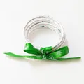 Primer plano de pulseras navideñas de silicona unidas con una cinta verde de copos de nieve - Árbol