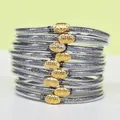 Gros plan de 9 bracelets superposables en silicone pailleté argenté avec boucles lotus dorées. - Pack de 9 Pièces / Gris foncé