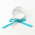 Detalle de pulseras navideñas multicapa de silicona con copos de nieve y cinta azul verdoso - Azul