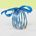 Close-up of blue glitter-filled silicone bangles tied with a blue satin ribbon bow. - 5 Pieces / Lake Blue