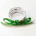 Detalle de pulseras navideñas de silicona multicapa con un lazo de cinta verde de copos. - Blanco