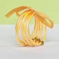 Detailed view of 5-layer gold glitter silicone bangles with an orange ribbon bow - 5 Pieces / Mustard Yellow
