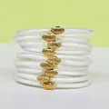 Close-up detail of a 9-layer white glitter silicone bangle set featuring gold lotus buckles - White