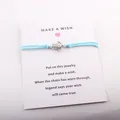 Détail d'un bracelet de vœux tortue avec cordon bleu clair sur une carte de cadeau - Bleu clair