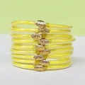 Close-up of 9 stackable yellow silicone glitter bangles with gold lotus clasps. - Yellow