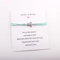 Détail du bracelet de vœux tortue avec cordon turquoise sur carte cadeau porte-bonheur - Vert Marin