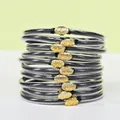 Set di 10 bracciali rigidi in PVC nero con eleganti chiusure a loto dorate. - Confezione da 10 / Nero