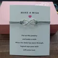 Detailed macro view of a silver infinity charm cord bracelet on a white Make a Wish card - Infinity Symbol (EB0168) / Gray