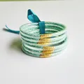 Close-up of 6 mint green glitter silicone bangles tied with a matching teal silk ribbon - Emerald