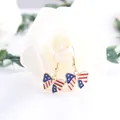 Detailed close-up of enamel American flag bow dangle earrings on a white rose background - Bowknot Shape