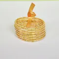 Macro detailed view of six-layer gold glitter silicone bangles with orange ribbon tie - Gold
