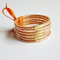 Close-up of orange glitter silicone bangles with gold-tone accents. - Orange Red