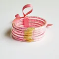 Detail view of 6-layer pink glitter silicone bracelets with a matching ribbon bow tie. - Pink
