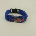 Close-up detail of a blue braided paracord bracelet featuring a metal US flag plate - Blue