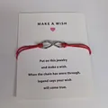 Infinity symbol wish bracelet with red adjustable cord on a white greeting card. - Infinity Symbol (EB0168) / Red