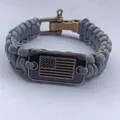 Detalle de una pulsera de paracord gris con una placa de bronce de la bandera de EE. UU. - Gris