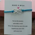 Handmade infinity symbol blue cord bracelet displayed on a Make a Wish blessing card - Infinity Symbol (EB0168) / Aquamarine