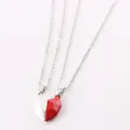 Macro view showing the magnetic attraction of silver and red heart pendants for couples. - White And Red Sailboat Pendant
