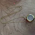 Vue détaillée d'un médaillon flottant en verre et acier doré avec chaîne serpent - 25 mm doré avec chaîne serpent